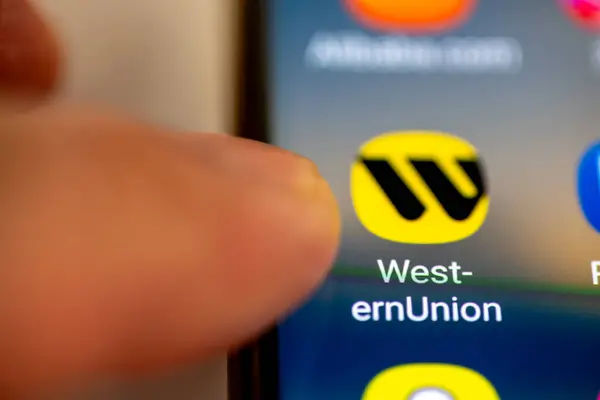 stock image London. UK- 07.28.2024. The American financial services, money transfer app Western Union on the screen of a mobile phone with a finger pointing at it.