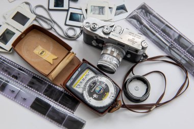 Londra mı? UK- 09.03.2024. Klasik Leica kamerası, film negatifleri ve beyaz olarak izole edilmiş slaytlarla ışık ölçer..