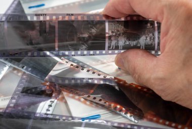 İşlem sonuçlarını incelemek için elinde siyah beyaz film şeridi tutan bir kişi..