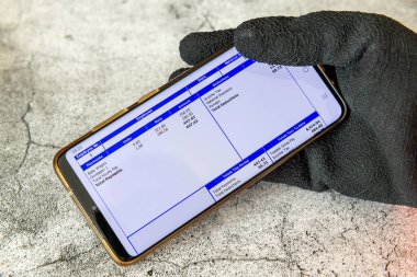 Londra mı? UK- 09.12.2024. İş eldiveni takan bir işçi elinde dijital maaş bordrosuyla cep telefonu tutuyor..