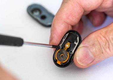 Tornavida kullanarak kablosuz kulaklık tamir eden bir teknisyene yaklaş..