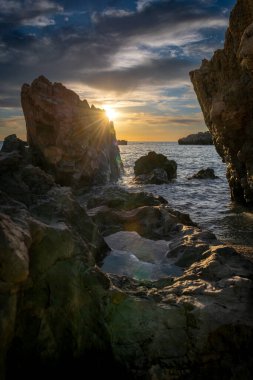 Gün batımında bir deniz manzarası. Güneş ışınları ve gökyüzü bir kaya havuzunda yansıyor. Bir doğa, ekoloji, çevre geçmişi.