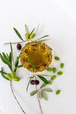 Kristal cam kasede zeytin yağı, dallarda yeşil ve siyah zeytin ve beyaz zeytinlerde izole edilmiş yeşil zeytin..