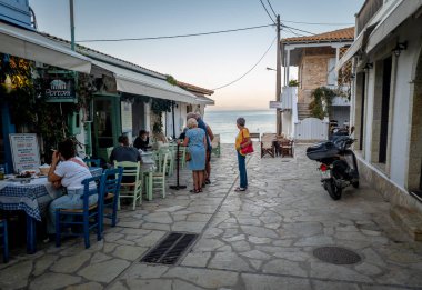 Lefkada, Yunanistan... 10.15.2024. Köy tatil beldesi Agios Nikitas 'ın ana caddesi sahil şeridine uzanan restoran ve barlarla doluydu..