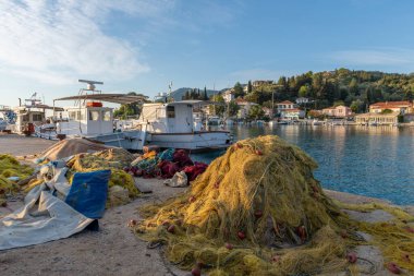 Geleneksel balıkçı teknesi ve Yunanistan 'ın Lefkada adasındaki Lygia köyünün deniz manzaralı liman iskelesinde kurutulmuş balık ağları..