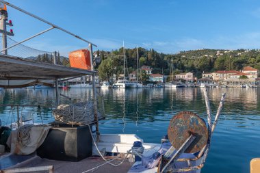 Lygia köyü limanı, Lefkada adası, Yunanistan, ön planda geleneksel balıkçı teknesiyle deniz kenarındaki binaları gösteriyor,