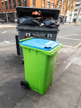 Londra mı? UK- 12.29.2024. Sokakta toplanmayı bekleyen bir restoranın çöp kutuları, genel atık için siyah çöp kutusu ve geri dönüşüm için yeşil çöp kutusu..