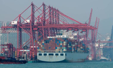 Hong Kong. Çin... 02.18.2025. Gemi Hong Kong Limanı 'ndaki vinçlere yanaşmış bir kargo gemisine konteynerleri yüklemek ya da boşaltmak için çalışıyor..