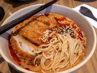 Bir kase acılı biberli, baharatlı erişte çorbası, kızarmış porto pirzolası ve çıtır çıtır bir kaplama..