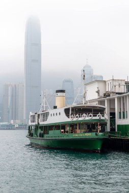 Hong Kong. Çin... 02.21.2025. IFC gökdelen manzaralı Tsim Sha Tsui Rıhtımı 'na yanaşan bir yıldız feribotu..