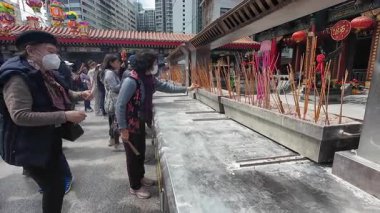Hong Kong. Çin - 02.24.2025. Shik Sik Yuen Wong Tai Sin Tapınağı 'na gelen ziyaretçi kalabalığını kapatın ve ana tapınağın önündeki tanrılara tütsü ve dua edin..