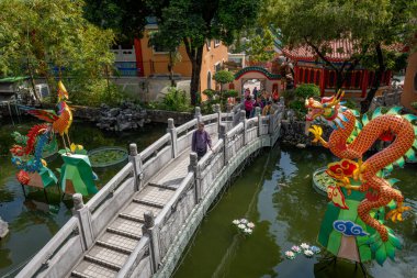 Hong Kong. Çin - 02.24.2025. Geleneksel Çin tarzı taş köprü ve ejderha Phoenix 'in yüksek açılı görüntüsü Wong Tai Sin Tapınağı kompleksindeki Good Wish Garden göletine kurulmuştur.