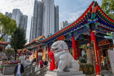 Hong Kong. Çin... 02.24.2025. Wong Tai Sin Tapınağı 'na genel bir bakış, Koruyucu aslan heykelleri, modern apartman bloklarının aksine geleneksel Çin mimarisi.