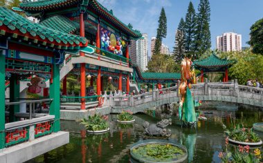 Hong Kong. Çin... 02.24.2025. Shik Sik Yuen Wong Tai Sin Tapınağı 'ndaki İyi Dilekler Bahçesi' nde geleneksel Çin pavyonlarını ve göletin üzerindeki taş köprüyü gösteriyor..