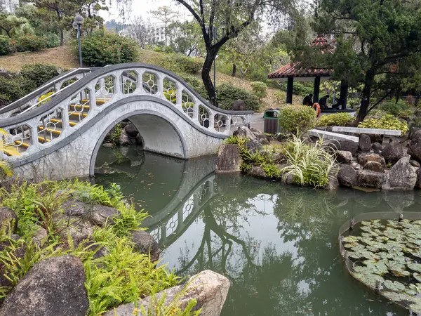 Hong Kong. Çin - 02.23.2025. Sha Tin Park 'ın uzak ucundaki Çin bahçesinde güzel bir kemer taşı köprüsü var..