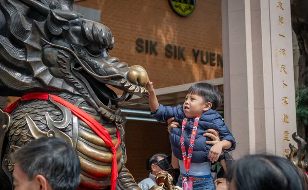 Hong Kong. Çin... 02.24.2025. Wong Tai Sin Tapınağının girişindeki ejderha heykeline şans getirmesi için bir çocuk kaçırıldı..