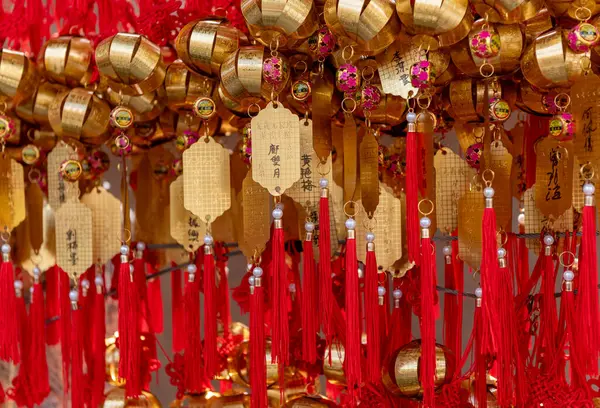 Hong Kong. Çin... 02.24.2025. Sik Sik Yuen Wong Tai Sin Tapınağındaki hacıların isimlerinin yazılı olduğu dua etiketlerini ve çanlarını kapatın..