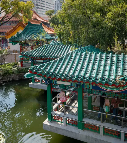 Hong Kong. Çin... 02.24.2025. Wong Tai Sin Tapınağı kompleksinde Çin tarzı pavyonların çatı ve İyi Dilekler Bahçesi göletinin yüksek açılı manzarası.