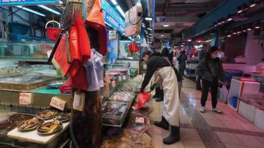 Hong Kong. Çin - 02.25.2025. Tai Po Hui Market 'in deniz ürünleri bölümünde müşteriye tatlı su karidesi satan bir tezgahtar. Tai Po, Yeni Bölgeler.