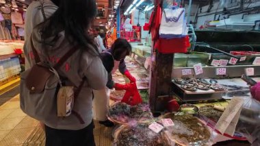 Hong Kong. Çin - 02.25.2025. Tai Po Hui Market 'te bir tezgahtar, ıslak bölümde, canlı tatlı su karidesleri almak için müşteriye servis yapıyor..