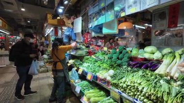 Hong Kong. Çin - 02.25.2025. Tai Po Hui pazarının meyve ve sebze reyonundan taze sebze alan bir adam..