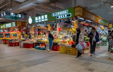 Hong Kong. Çin - 02.25.2025. Tai Po Hui Pazarı 'nın meyve ve sebze bölümünün iç manzarası. Ziyaretçiler taze ürünleri satın alıyor..