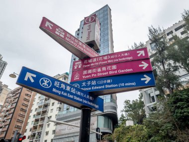 Hong Kong. Çin... 02.26.2025. Bir Mong Kok semti caddesi yön tabelası tren istasyonlarına ve yerel işaretlere giden yolu gösteriyor..