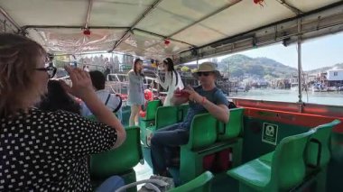 Hong Kong. Çin... 02.27.2025. Tai O balıkçı köyü, Lantau Adası 'nda tekne turunda selfie çeken turistler.