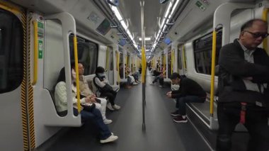 Hong Kong. Çin... 02.28.2025. Bir MTR treninin içi vagonlarda açık bağlantıları olan yolcuları gösteriyor..