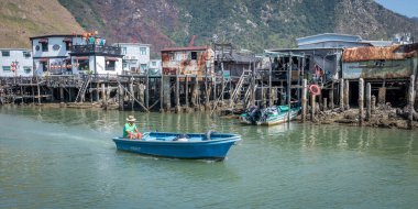 Hong Kong. Çin... 02.27.2025. Tai O balıkçı köyünün su yolundan küçük bir tekne geçiyor. Evleri su kenarına asılmış..