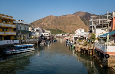 Hong Kong. Çin... 02.27.2025. Lantau Adası 'ndaki bir balıkçı köyü olan Tai O köyünün genel manzarası, suyun üzerinde geleneksel yerleşim yapıları bulunan gelgit deniz kanalını gösteriyor..