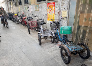 Hong Kong. Çin... 02.27.2025. Lantau Adası 'ndaki Tai O köyünde üç tekerlekli bisiklet ve bisiklet. Birincil ulaşım aracı, arabasız balıkçı köyüdür..