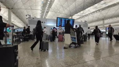 Hong Kong. Çin... 03.05.2025. Hong Kong Uluslararası Havaalanı Terminali 1 kalkış salonuna gelen yolcular, uçuş bilgilerini kontrol etmek için dijital ekranı kontrol ediyorlar..