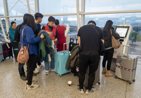 Hong Kong. Çin... 03.05.2025. Hong Kong Uluslararası Havalimanı Terminali 1 'deki hava yolcuları kişisel servis kontrolü ve havayolu personeliyle birlikte indirme makinelerini kullanarak müşterilere yardım ediyor..