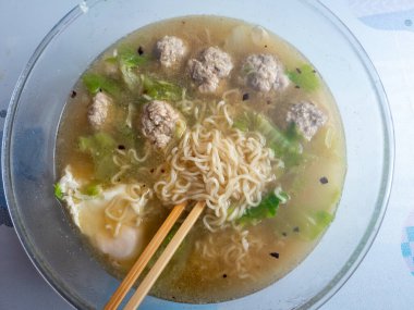 Bir kase ev yapımı hazır şehriye çorbası domuz köftesi, haşlanmış yumurta, Çin yaprağı ve acı biber yağı..