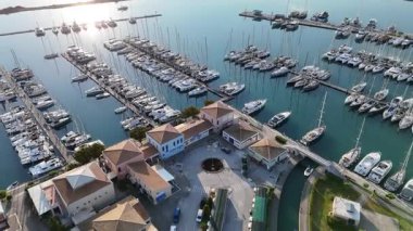 Lefkada Marina 'nın sabah ışığında yükselen, eğimli klibi demirli tatil yatlarını ve binalarını gösteriyor. Lefkada, Yunanistan.