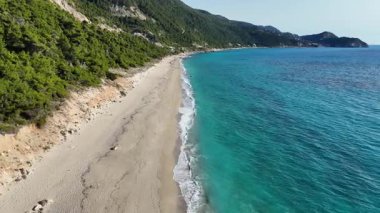 Yunanistan 'ın Pefkoulia, Lefkada adasında güzel bir sahil şeridi boyunca uzun, neredeyse ıssız, kumlu bir plajın alçalmakta olan havası..