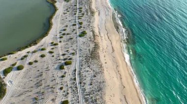 Bir yamacında deniz ve kumsal olan bir bataklığın eğimli hava klipsi..