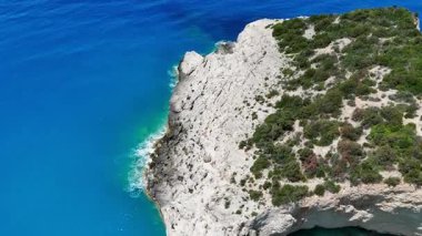 Engebeli kayalık bir burnun üzerinden uçarak güzel mavi denize iniyor..