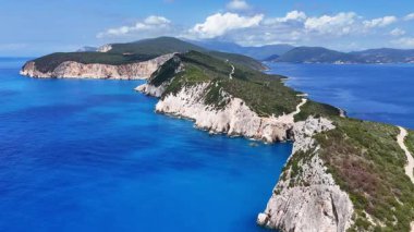 Engebeli bir Yunan adası pelerininin hava görüntüleri. Her iki tarafında derin mavi denizi olan bir burnu var.. 