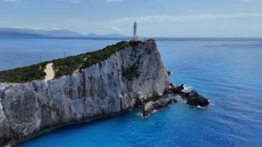 Lefkada, Yunanistan... 05.19.2025. Lefkatas Burnu 'nun üzerinden uçan hava, kayalıkların üzerindeki ışık evini ve güzel mavi denizi gösteriyor..