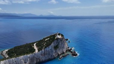 Lefkada, Yunanistan... 05.19.2025. Cape Lefkatas 'ın geri çekilen bir klibi uçurumun tepesindeki deniz feneri ve derin mavi deniz manzaralı..