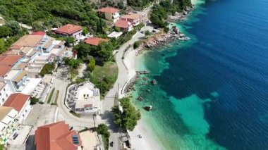 Lefkada, Yunanistan... 05.19.2025. Vassiliki köyü sahil yolunun bir tarafında tatil evleri, diğer tarafında küçük plajlar ve mavi deniz var..
