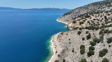 Kayalık bir dağ ve mavi deniz arasında terk edilmiş bir sahil yolunun dramatik, güzel hava manzarası..