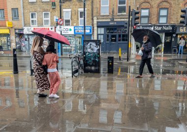 Londra mı? Uk-24 Temmuz. 2025 yılı. Başkentte sıcak hava dalgası üstüne yaz yağmuru. Yayalar şemsiyeler altında kuru kalıyor..