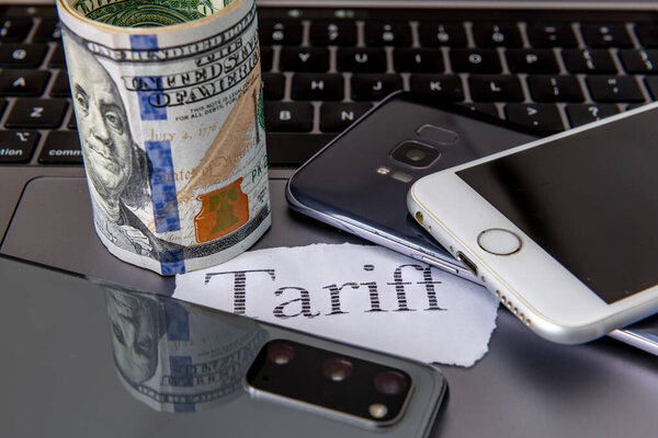 Тарифная инфляция, стоимость жизни с печатным словом тариф, ноутбук, различные смартфоны и рулон банкнот в долларах США .