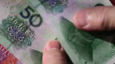 50 ve 100 Çin Yuan 'ı banknotları sayan birinin yakın çekim görüntüleri..