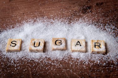 A close up of the word sugar sprinkled with granulated white sugar.