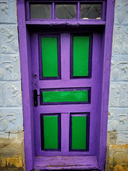 Bright purple-green wooden doors in a rustic old house close-up