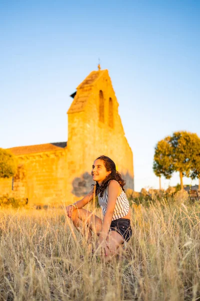 Country girl on a meadow with a church in the background
